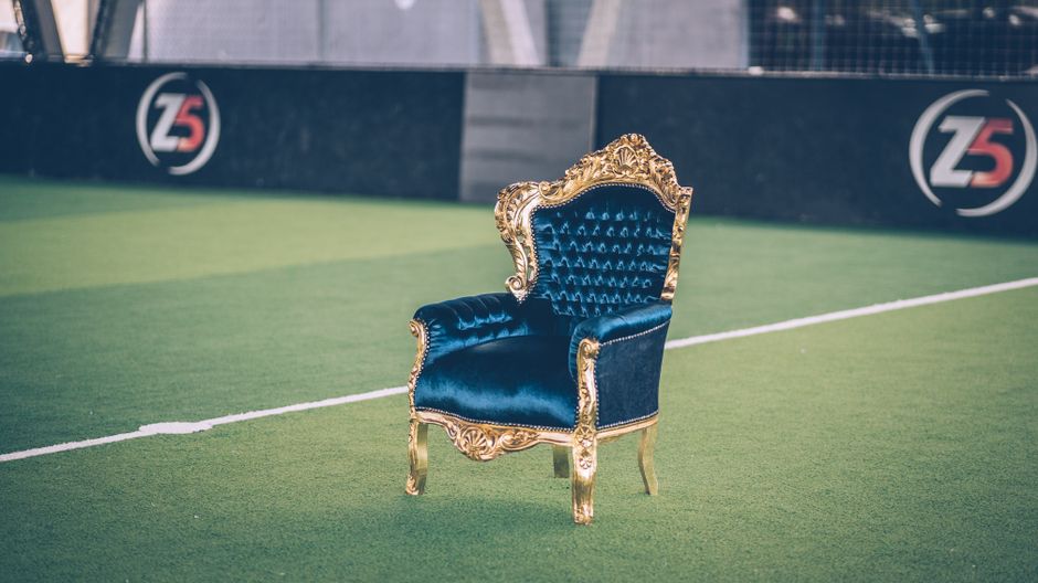 A white tufted fabric sofa with rolled arms and dark wooden legs positioned against a white paneled wall in a well-lit room. The sofa's surfaces appear clean and well-maintained, reflecting a professi
