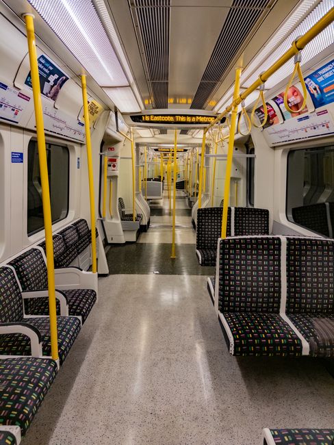 The image shows the entrance to a London Underground train at Bounds Green tube station, with the train doors open revealing the interior. The platform features a white wooden station canopy with deco